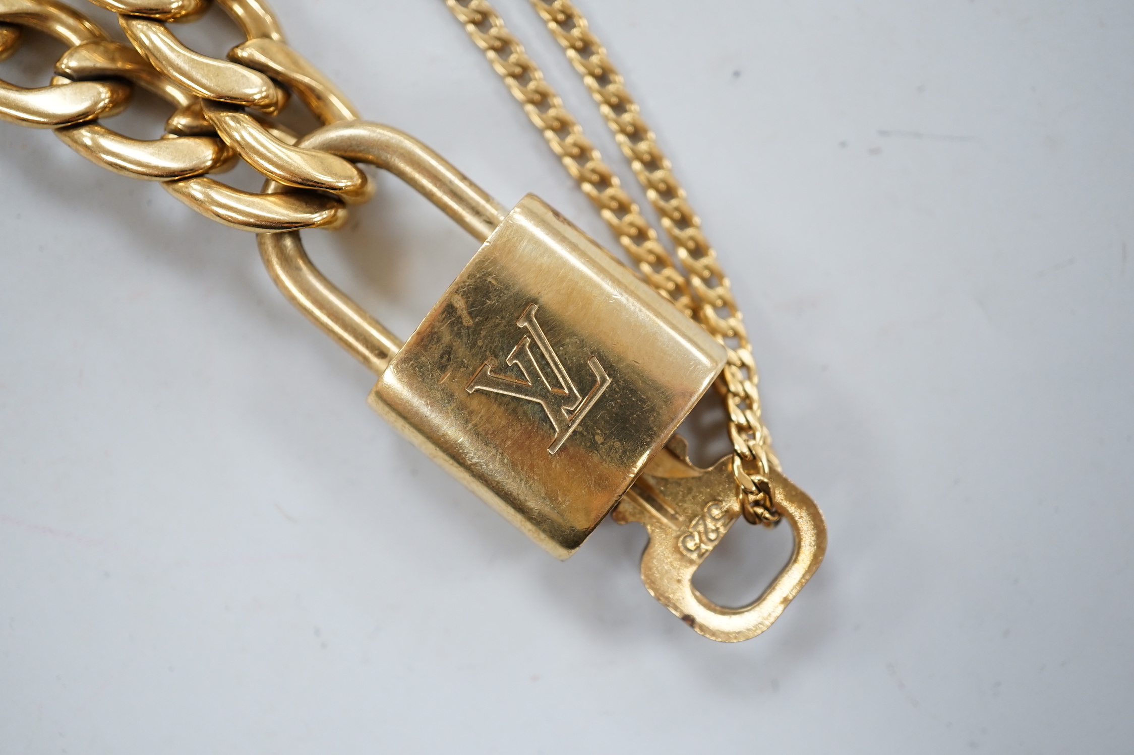A Louis Vuitton gilt metal key and padlock pendant, 36mm, on a Boutique Secondlife of London, curb link chain, chain 40cm.